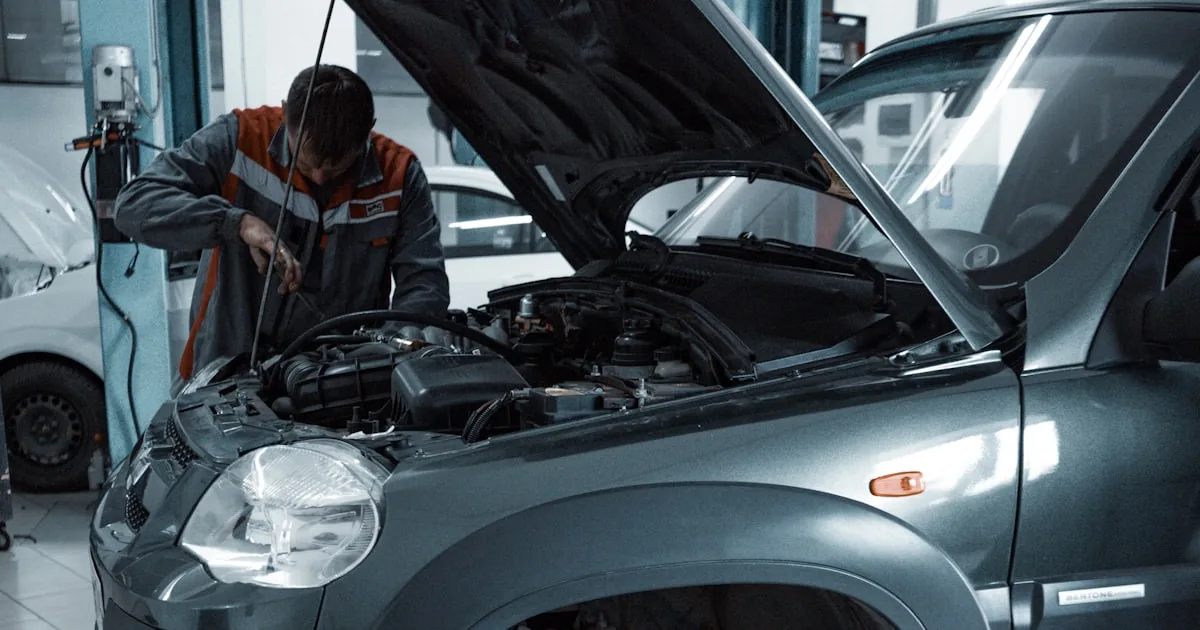 SUV cu capota ridicată într-un service auto, cu un tehnician lucrând la motor